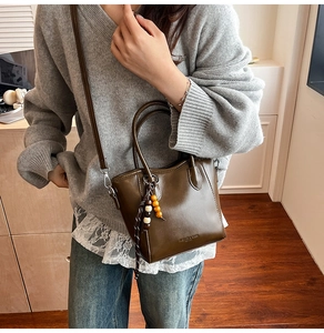 Détail du sac seau vert olive avec breloque en bois et bandoulière amovible élégante