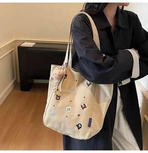 Detail of canvas tote bag with colorful animal embroidery and plush bear charm