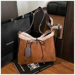 Close-up of brown faux suede shoulder bag with soft white faux fur trim and bow detail