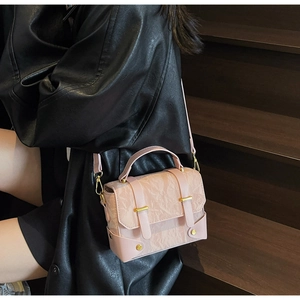 Détail d'un sac à main rose structuré avec texture plissée et fermoir en métal doré
