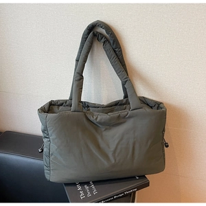 Detailed view of dark olive green quilted nylon tote bag with drawstring side adjustments