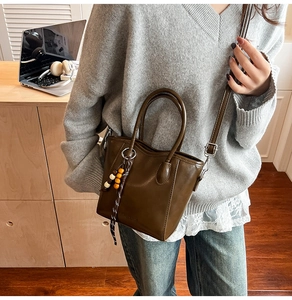 Sac seau marron foncé avec breloque en perles présenté dans un cadre de bureau