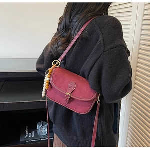 Close-up of burgundy matte crossbody bag with retro buckle and colorful wooden beads