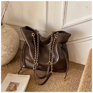 Close-up of brown leather bucket bag with gold chain strap and drawstring detail