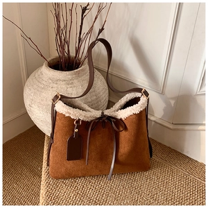 Detail of suede underarm bag with white faux fur trim and elegant bow tie drawstring