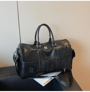 Détail du grand sac de voyage noir montrant le simili cuir texturé et la bandoulière