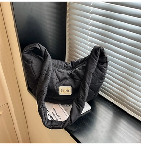 Detail shot of heart-shaped quilting and golden S-logo plaque on the black padded nylon bag