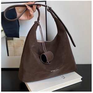 Close-up of dark brown lychee texture leather underarm bag with cylindrical charm