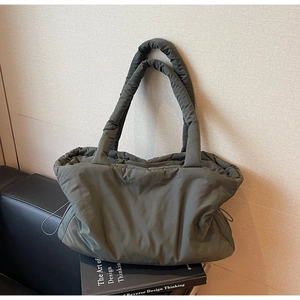 Detail of army green quilted nylon tote bag placed on a black design book