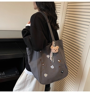 Detail of dark grey canvas tote bag with cat embroidery and plush bear charm