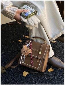 Retro brown leather handbag featuring a plush bear pendant and elegant gold metal buckle