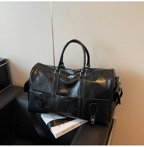 Détail du sac de voyage en similicuir noir avec texture vintage et bandoulière