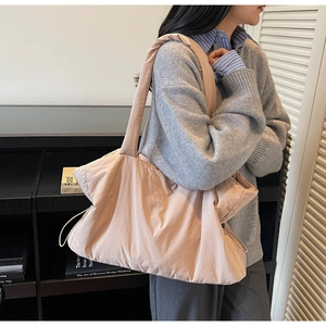 Detail of pink-beige quilted tote bag showing side drawstring and soft puffy texture