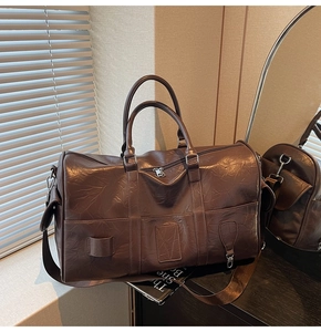 Détail d'un grand sac de voyage en cuir PU marron foncé plissé avec bandoulière