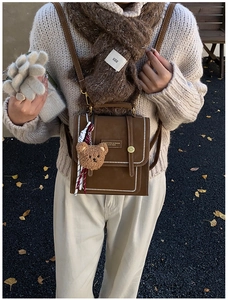 Detail of vintage brown leather backpack with white stitching and plush bear charm