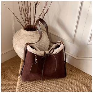 Detail view of suede shoulder bag with cream faux fur trim and elegant leather bow knot
