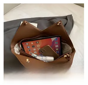 Macro shot showing large storage capacity of brown leather tote bag with tablets and items