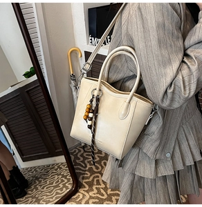 Sac seau minimaliste en cuir blanc crème avec perles en bois et détail de gland tissé
