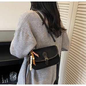 Detail of black vintage crossbody bag with decorative wooden beads and gold hardware