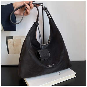 Close-up of matte black hobo bag with a mini round charm and fashion logo print