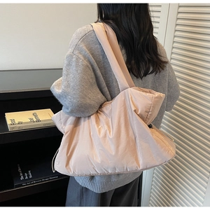Quilted tote bag showing soft padded texture and side drawstring detail in a room setting