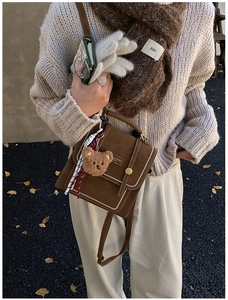 Detail of vintage brown mini backpack with golden metal plate and white stitch trim decor