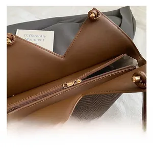 Close-up of brown leather patchwork tote bag showing metal zipper and gold hardware detail