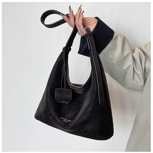 Detailed view of black matte leather tote bag with branded charm and handle strap