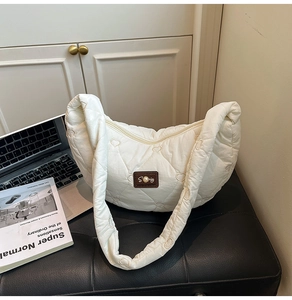 Detail of cream quilted puffer bag with heart embroidery and leather brand logo patch