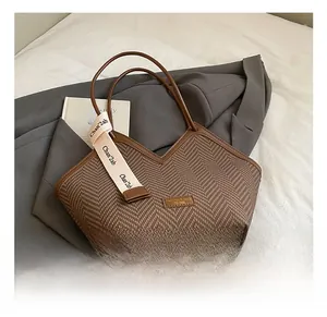 Detail of vintage tote bag with houndstooth stitching and decorative silk scarf on handle