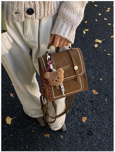 Detail of vintage brown leather backpack with contrast stitching and teddy bear charm