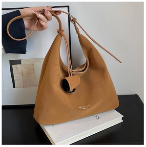 Detail of soft brown leather texture and logo on this large crossbody hobo bag