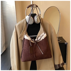 Chic brown suede bucket bag with white faux fur trim and bow detail on display