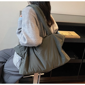 Close-up of olive green quilted puffy tote bag showing large capacity on model
