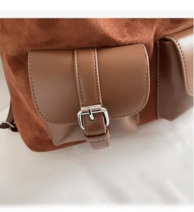 Detail of suede and leather stitching with silver metal buckles on a brown tote bag