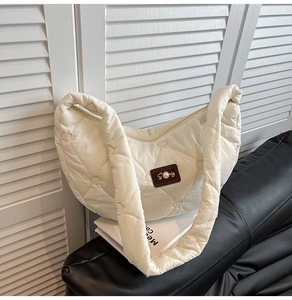 Detail of cream quilted puffer bag with heart stitching and pearl logo patch