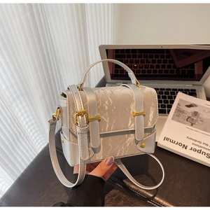 Détail d'un sac à main argenté effet froissé avec boucles dorées et bandoulière fine