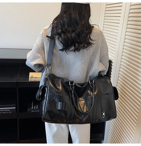 Vue portée d'un grand sac de voyage en cuir PU noir brillant avec bandoulière réglable