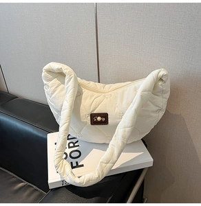 Close-up of heart-stitched quilted texture and decorative pearl patch on cream nylon bag