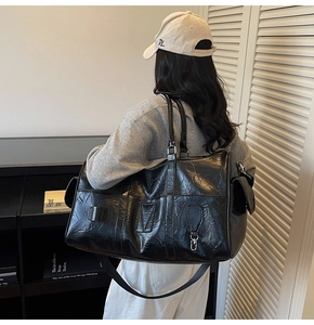 Détail du sac de voyage en cuir froissé noir avec bandoulière et poche zippée latérale