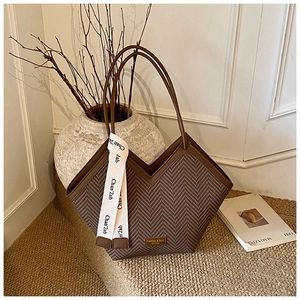 Detail view of brown tote bag with herringbone texture and decorative ribbon strap