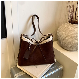 Detail of dark brown suede tote with faux shearling trim and delicate leather bow accent