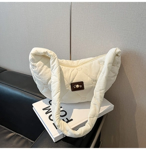 Detailed view of white heart-quilted crossbody bag with pearl accent on leather patch