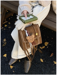Close-up of vintage brown leather backpack with contrast stitching and golden clasp detail