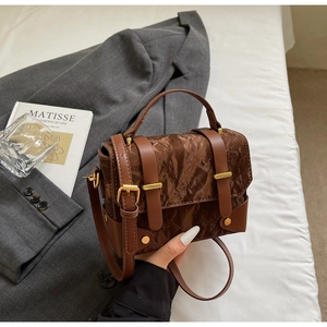 Détail du sac à main en cuir marron texturé avec boucle dorée et bordure lisse