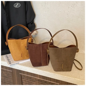 Detail view of retro bucket bags in ginger, coffee, and taupe suede with round buckles