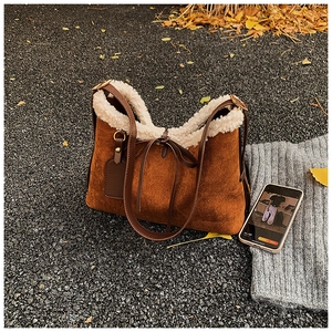 Detail view of brown suede underarm bag with white fleece trim and golden hardware
