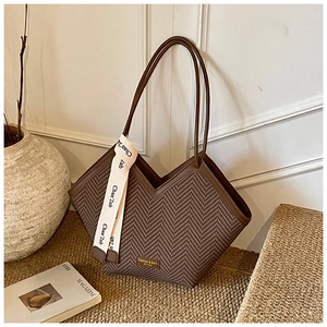 Close-up of brown woven texture tote bag with golden metal plate and silk ribbon detail