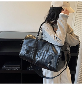 Détail du sac de voyage en cuir froissé noir montrant la bandoulière et la poche magnétique