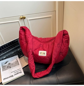 Detail of red quilted hobo bag with heart embroidery and pearl letter S metal buckle